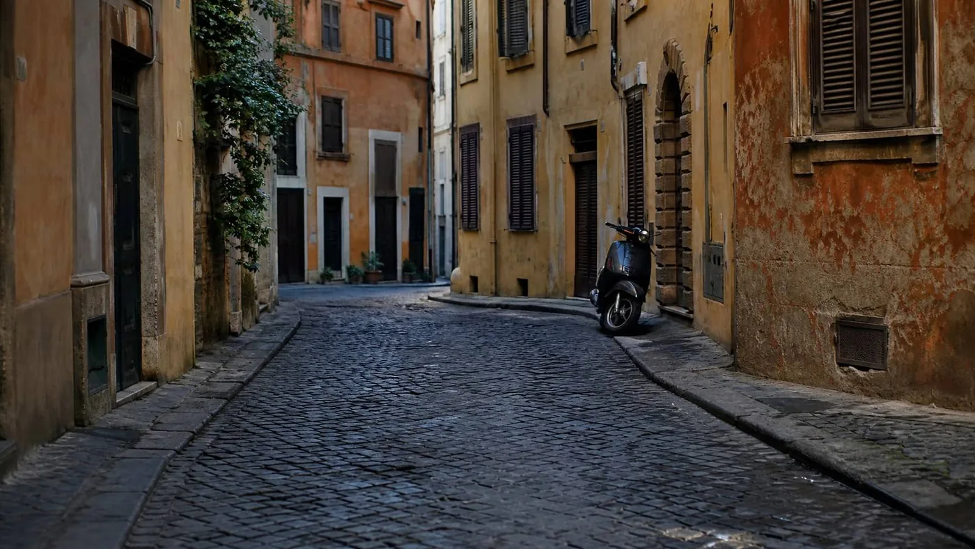 A Roman side street at first light, shutters still closed. This is the hour the palace opens on. It is not the palace.