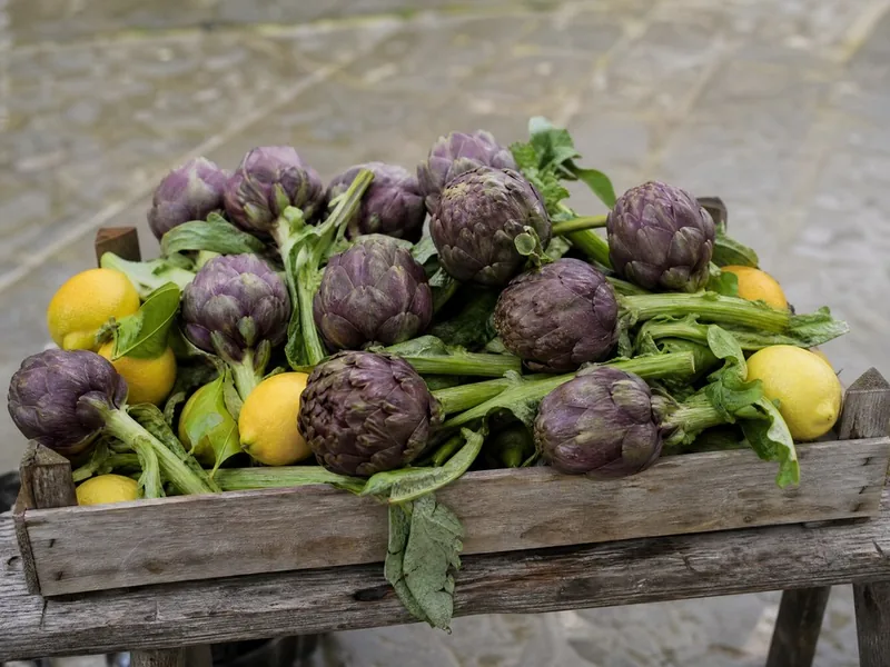 Roman artichokes and lemons in a wooden crate