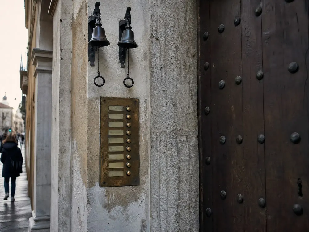 A brass bell panel beside a heavy studded door