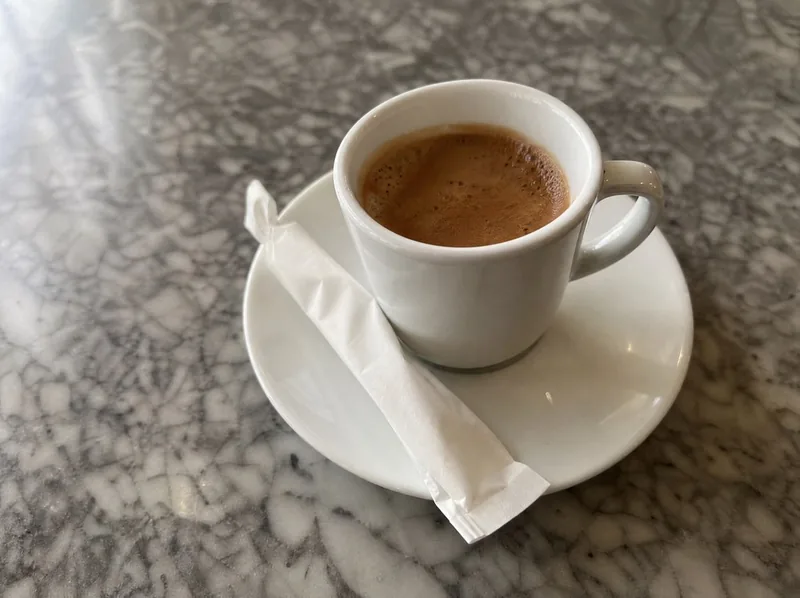 An espresso cup and a sugar packet on a marble table top