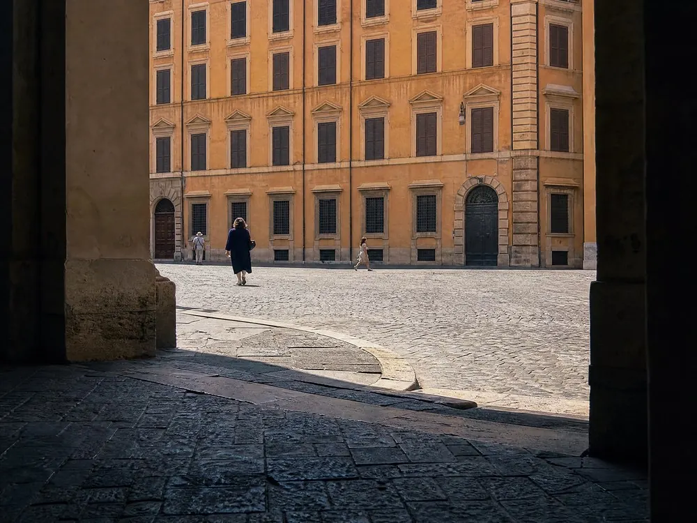 A small sunlit Roman square seen from the shade at its edge